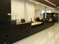 an empty library with desks and bookshelves filled with books, plants and flowers