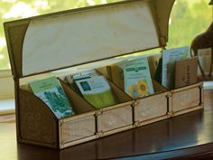 a wooden box filled with lots of books on top of a table next to a giraffe