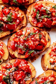 several pieces of bread with tomatoes and cheese on them sitting on a white table top