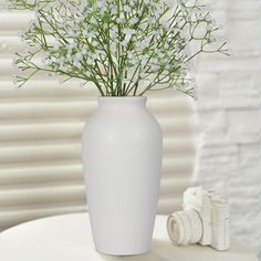 a white vase sitting on top of a table filled with lots of small white flowers