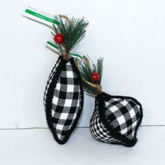 two black and white checkered ornaments hanging from a branch with red berries on it