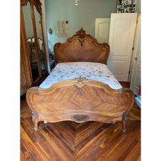 a bed sitting on top of a hard wood floor next to a dresser and mirror