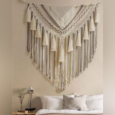 a bed with white sheets and tassels hanging on the wall