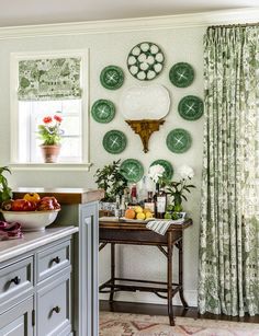 a kitchen with green plates on the wall and curtains in the window, along with an island