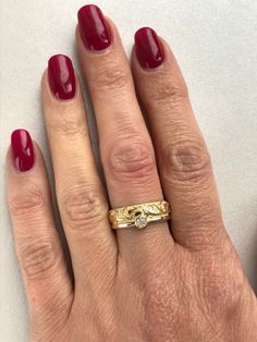 a woman's hand with a gold ring and red nail polish on her nails