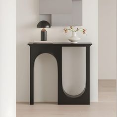 a black and white table with vases on it in front of a wall mounted mirror