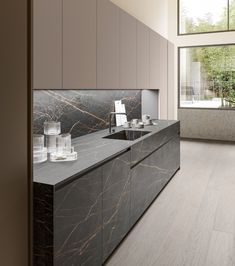 a modern kitchen with marble counter tops and cabinets in grey tones, along with wooden flooring