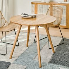 a wooden table with two chairs next to it and a rug on the floor in front of it