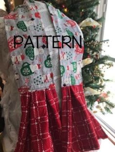 the back of a dress with red and green patterns on it, next to a christmas tree