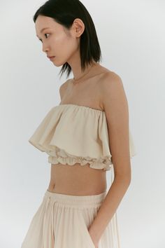 Our signature convertible ruffle top is so versatile, it can adjust to any mood. Manipulated into a countless number of ways, this elasticized top can be worn as a simple tube top, to off the shoulder or even as an asymmetric one shoulder. Choose to tie the long ties into a bow or over the shoulder into spaghetti straps or halter - the possibilities are endless. Made in our dandelion cotton - this fabric features a lightly brushed, textured exterior while maintaining a soft breathable interior. Cotton Ruffle Top, Neutral Loungewear, Diwali 2024, Ruffle Tube Top, Slouch Socks, Pretty Blouses, Strapless Tops, Stylish Dress Designs, Brushed Cotton