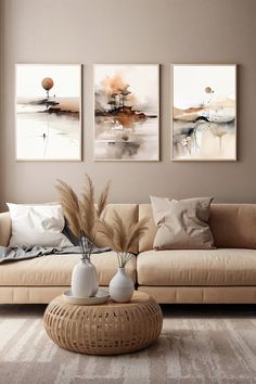 three paintings hang on the wall above a couch in a living room with a wicker coffee table