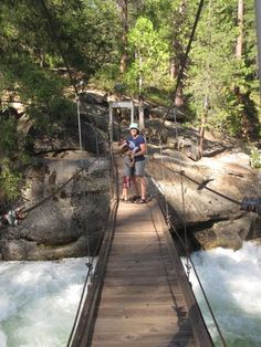 a man standing on a suspension bridge over a river