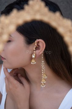 The gold-plated kundan jhumkis are traditionally inspired by the rich Indian Heritage of jewelry making. The design of the bridal jhumkis earrings features pearl hangings and a top encrusted with kundan. These ethnic jhumkis have a gold-plated pearl chain that gives them a delicate and elegant look. The richly traditional design is versatile and can be paired with almost anything Indian.  Closure - Push Back Handcrafted in Jammu and Kashmir  Paisley Pop travels the depths of India to learn techniques and crafts from deep down the local markets and villages. We give utmost importance to our quality and packaging. Our goal is to make sure you receive exactly what you are looking for and for your experience to be a special and memorable one. We are ready to help and advise you through your pu Gold Jewellery Bridal Indian, Simple Indian Earrings, Jhumka Designs Gold Indian, Indian Aesthetic Jewellery, Traditional Earrings Indian Jewelry, Indian Pearl Earrings, Ethnic Jewelry Indian, Indian Bridal Earrings, Big Jhumka Earrings