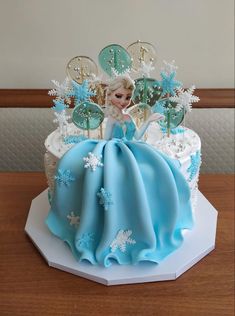 a frozen princess cake with snowflakes and decorations on the top is sitting on a table