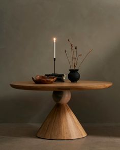 a wooden table topped with a candle and two vases