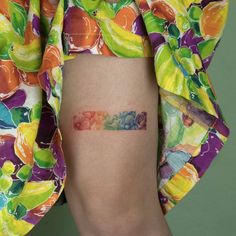 a person with a tattoo on their leg that has fruit in the shape of a rainbow