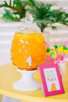 a table topped with a glass filled with orange juice and straws on top of it