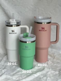 three travel mugs sitting next to each other on a white blanket with the same size and color