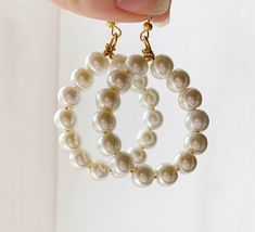 These beautiful oversized hoop pearl earrings are the ideal statement earrings for lovers of contemporary pearl jewellery and large dangle earrings. Vintage inspired 8mm white pearls sit upon golden wire, wrapped to a gold plated hook to create a beautiful dangle earring upgrade on classic hoop earrings. The perfect gift for pearl dangle earring fanatics. Minimalistic and geometric in style, the simplistic nature of the beads combined with the bold statement shape of the hoop create the perfect bold dangle earring for lovers of minimalist contemporary earrings with a unique bold twist. Modern White Round Pearl Earrings, Modern White Pearl Earrings, Pearl White Round Earrings For Everyday, Minimalist Pearl Earrings For Parties, Everyday Round Pearl Chain Earrings, Minimalist Pearl White Earrings For Party, Chic White Earrings With Pearl Chain, White Pearl Charm Hoop Earrings, Pearl White Round Beaded Earrings