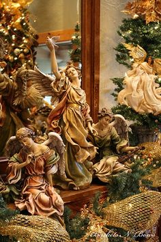 an assortment of christmas decorations on display in front of a mirror with angel figurines