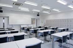 an empty classroom with desks and whiteboards on the walls, in front of a projector screen