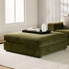 a living room with two green couches and a coffee table on top of it