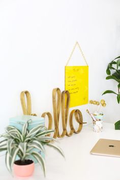 a white desk topped with a laptop computer next to a potted plant and a yellow sign