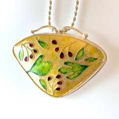 Enamel cloisonné pendant with sassafras leaves, red and purple berries, and a golden background. Set in fine silver Handmade Yellow Gold Enamel Necklace, Handmade Yellow Gold Enamel Necklaces, Handmade Gold Enamel Necklaces, Gold Enamel Round Pendant Necklace, Yellow Gold Enamel Oval Pendant Necklaces, Hand Painted Gold Jewelry Gift, Gold Hand Painted Jewelry Gift, Handmade Yellow Gold Enamel Jewelry, Unique Gold Enamel Jewelry