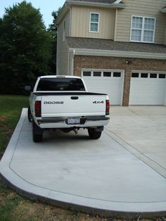 a white truck parked in front of a house with two garage doors on each side