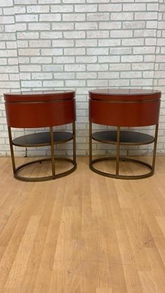 pair of round leather end tables with metal bases on wooden flooring in front of brick wall