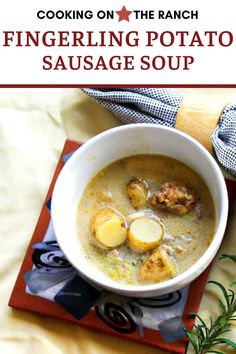 a white bowl filled with soup and potatoes on top of a red place mat next to a wooden spoon