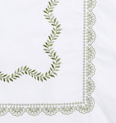 a white table cloth with green leaves and vines on the border, in front of a white background