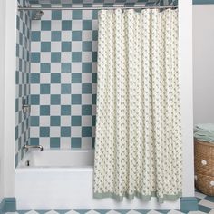 a bath tub sitting next to a white and blue tiled wall with a shower curtain