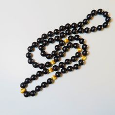 On offer is this beautiful Vintage 14kt. Yellow Gold Black Onyx Gemstone Necklace featuring large 10 mm Onyx Gems with large solid 14 karat yellow gold corrugated spacer beads. It measures a nice long 32 Inches in length with no clasp so it slips easily over your head. The lustrous and highly polished Onyx gems glow like glass and contrast nicely against the shiny 14 karat yellow gold beads. The necklace is hand knotted with black silk cord.  The 14kt yellow gold spacer beads measure a nice larg Gold Onyx Beaded Necklaces With Gemstone Beads, Classic Onyx Necklace With Black Beads, Gold Onyx Gemstone Beaded Necklaces, Gold Beaded Necklace With Black Onyx Beads, Gold Onyx Beaded Necklaces With Black Beads, Gold Pearl Necklace With Black Round Beads, Gold Onyx Beaded Necklace With Black Beads, Elegant Black Jewelry With 8mm Beads, Onyx Necklace With 8mm Round Beads