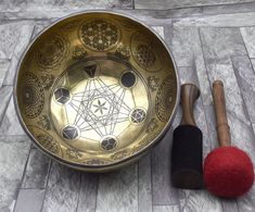 a metal bowl and two wooden mallets on a stone floor