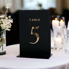 a table number is displayed on top of a table with candles and flowers in vases