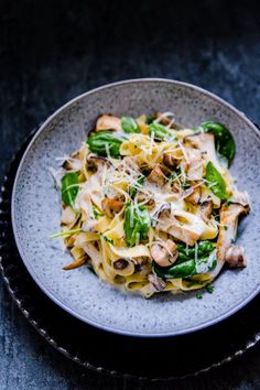 pasta with mushrooms, spinach and cheese in a bowl on a black tablecloth