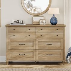 a bedroom with a dresser, mirror and lamp on it in front of a window