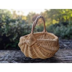 a wicker bag sitting on top of a wooden table next to bushes and trees