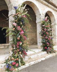 an arch covered in flowers next to a building