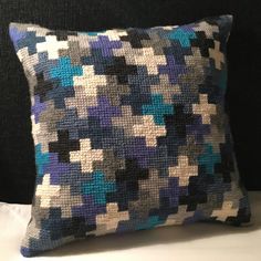 a blue and white pillow sitting on top of a black couch next to a wall