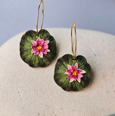 two pink flowers sitting on top of green leafy waterlily leaves in front of a white background