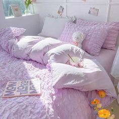 a bed with pink sheets and pillows in a bedroom next to a flower vase on the floor