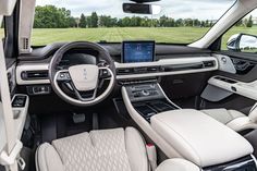 the interior of a car with all white leather seats and dashboard, including an electronic display