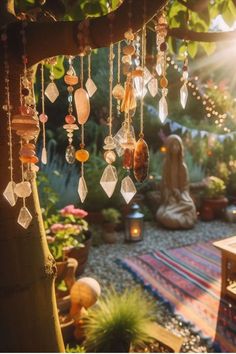 the sun shines brightly through an outdoor area with beads hanging from a tree and buddha statue in the background