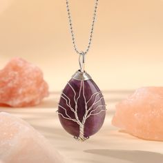 PLEASE NOTE: Our crystal stones are natural minerals and each crystal is unique. The internal ice cracks, pits, mineral points, and color differences of natural crystals are all formed naturally and are normal phenomena, which will not affect the efficacy, beauty and value of the crystal at all.This necklace is probably the most beautiful piece of jewelry you'll ever see. The intricate tree design weaved around the gorgeous purple crystal adds to this necklace's charm. Wear this magical piece ar Silver Gemstone Beads Crystals For Gift, Spiritual Rose Quartz Crystals With Natural Stones, Spiritual Rose Quartz Crystals, Spiritual Agate Crystals As Gift, Spiritual Agate Crystals For Gifts, Natural Quartz Stones Crystals As Gift, Spiritual Gemstone Teardrop Pendant Crystal Necklaces, Spiritual Teardrop Gemstone Crystal Necklace, Unique Crystal Stone Necklaces For Healing