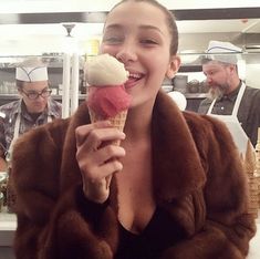 a woman eating an ice cream cone with other people in the background at a restaurant