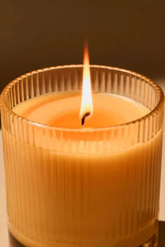 a lit candle sitting on top of a table next to a glass container filled with liquid