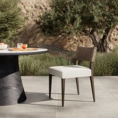 an outdoor table with two chairs next to it and a bowl of fruit on the table