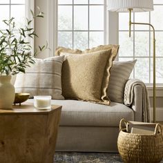 a living room filled with lots of furniture and pillows on top of a couch next to a window